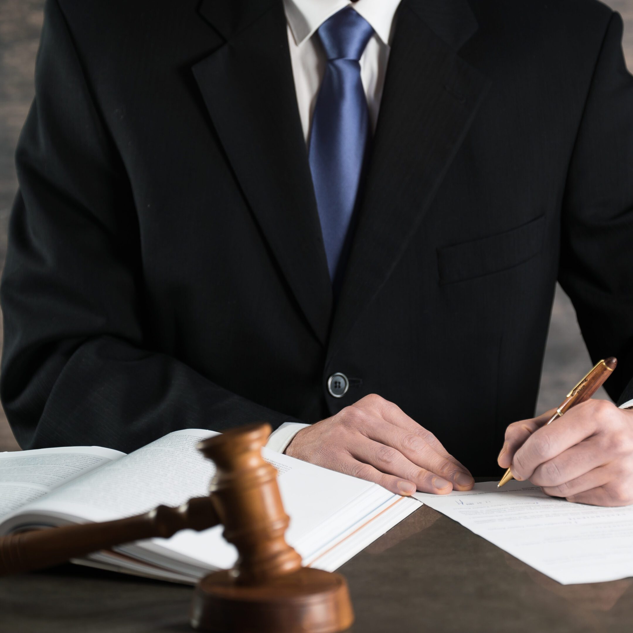 Lawyer writing at desk with gavel